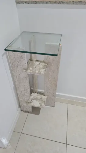 Mesinha com base em pedra e tampo em vidro.