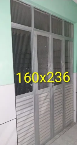 Porta de aluminio em veneziana na parte inferior e vidro canelado na parte superior.