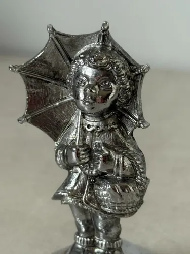estatueta em metal com menina e guarda-chuva