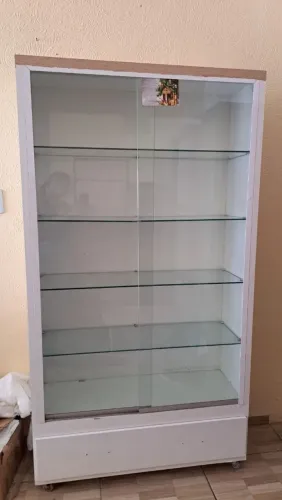 Vitrine expositora branca com estrutura em MDF  e prateleiras internas de vidro.