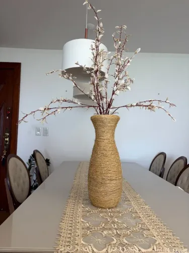 Arranjo com galhos e folhas secas em vaso revestido com sizal, finalizado em base de barro