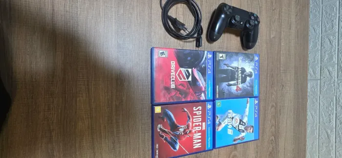 PlayStation 4, com um controle se borracheira e 4 jogos