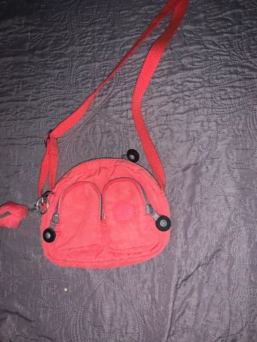 Bolsa Kipling, modelo Kalipe, com dois bolsos frontais com zíper e alça ajustável.