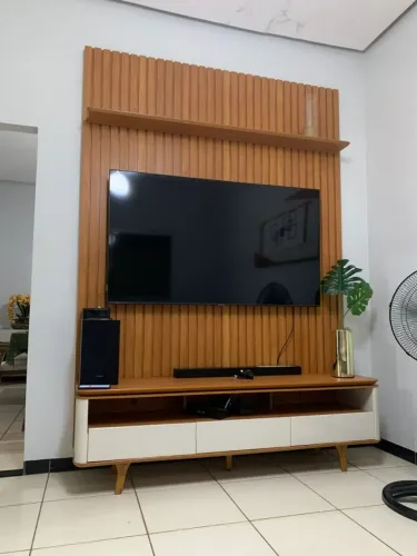 Rack para TV com ripado de madeira e 3 gavetas brancas.