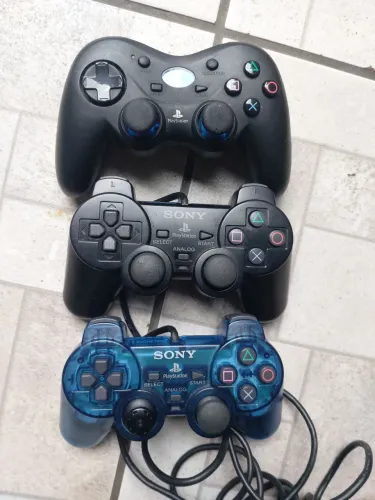 três controles de videogame do tipo DualShock modelos do PlayStation 2