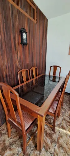 Mesa em madeira com tampo de vidro e seis cadeiras acochoadas.