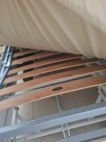 Cama hospitalar com colchão e grades.