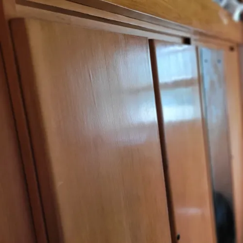 Guarda-roupas em madeira com quatro portas com cama  de solteiro sobre ele.