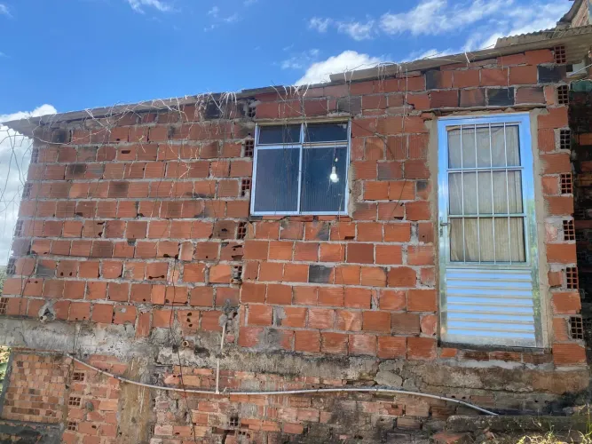 Casa em construção com sala, cozinha americana, 2 quartos e 2 banheiros.