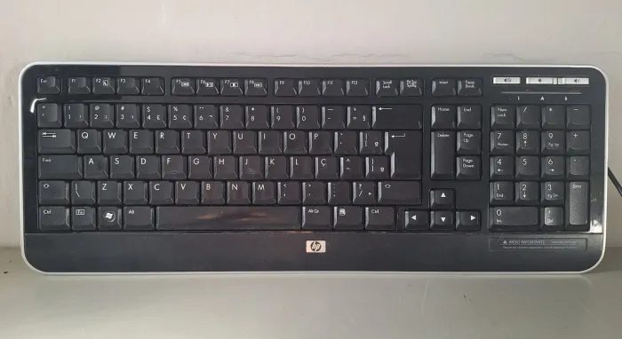 Teclado multimídia com fio HP KU-0841 na cor preta com bordas prata. 