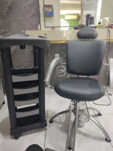 Um cadeira para cabeleireira e um carrinho auxilia