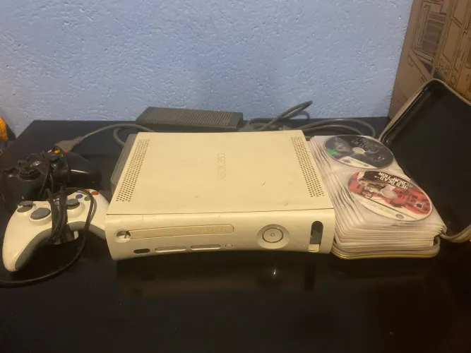 vendo xbox 360 branco, dois controles e um monte de jogo em uma pasta.