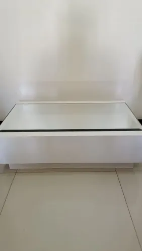 Mesa de centro branca com tampo espelhado e lateral em madeira laqueada.