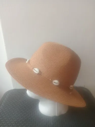 chapéu de palha bege com aba média a larga e aplicação de cordão com búzios.