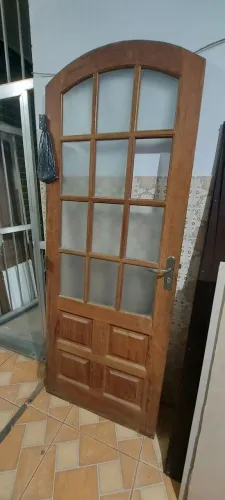 Porta de madeira maciça com dobradiças e vidros incluídos.