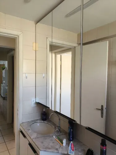Armário de Banheiro com espelho, bancada de pia e vaso sanitario com descarga acoplada.