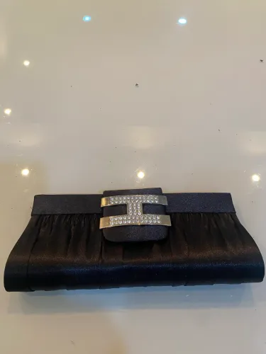 Esta é uma clutch de cetim preta com fecho de fivela decorativo.