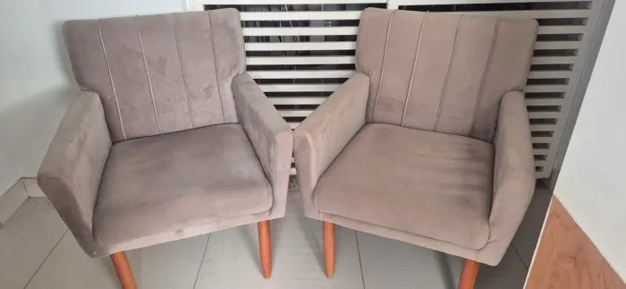 Duas poltronas de suede iguais com a base de madeira confortáveis