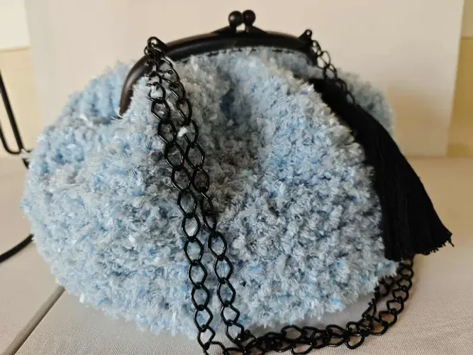 Bolsa de crochê com fecho da Vovó e alça de ombro em corrente. Possui tassel.