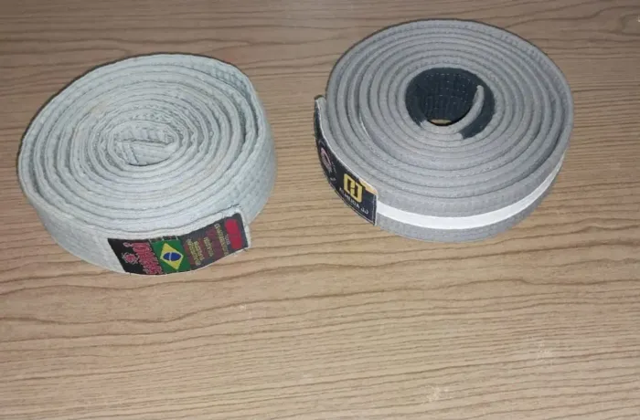 Vendo duas faixas de Jiu-jitsu uma cinza e outra cinza com branca 