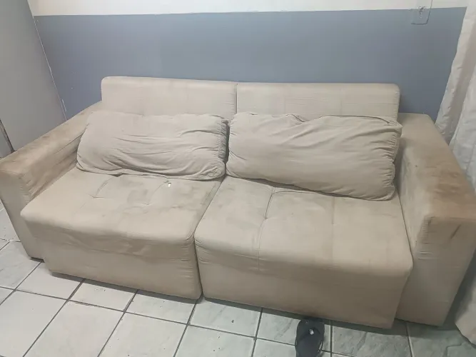É um sofá retrátil de três lugares na cor bege.. ele está bem conservado porém está sujo.