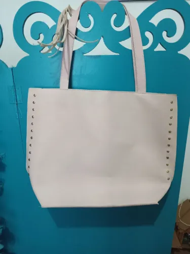 Bolsa de ombro rosa claro com detalhes em dourado e franjas