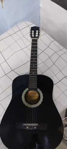 Violão de nylon, 6 cordas e acompanha um capo, 2 palhetas, afinador, correia e capa.