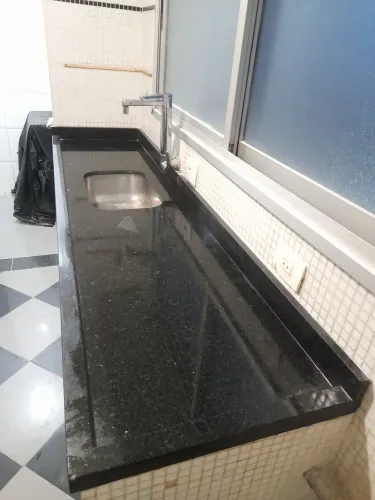 Bancada de cozinha granito preto com cuba de aço e torneira.