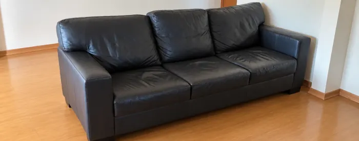 Sofá de couro legítimo preto, com 03 lugares e almofadas soltas no encosto. Conforto e ele