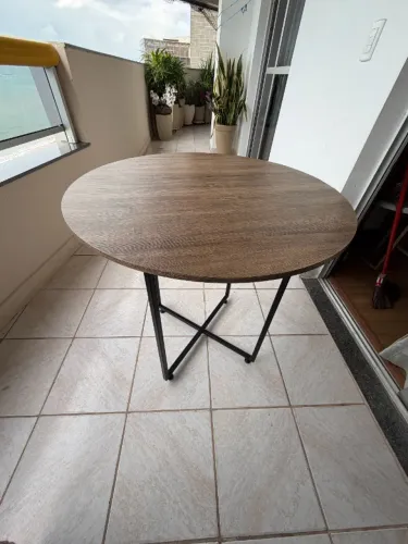 Mesa redonda estilo industrial, tampo amadeirado com base cruzada em metal preto