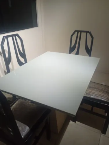 MESA DE JANTAR À VENDA<br>Mesa retangular com tampo de vidro branco e base central.