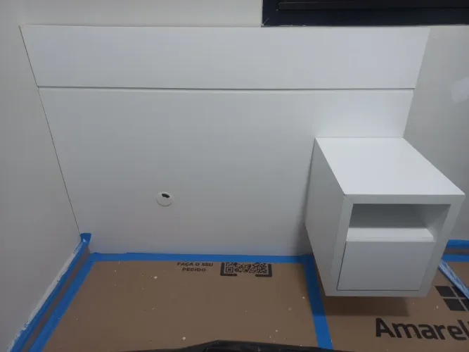 Cabeceira branca para cama de solteiro com mesinha de cabeceira.