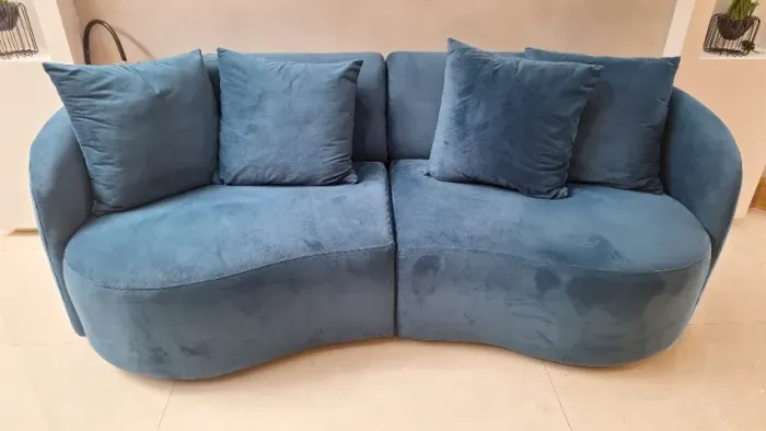 Sofá curvado em suede azul com almofadas