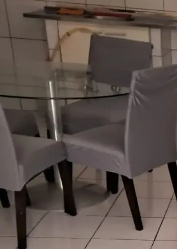 Mesa de vidro com 4 cadeiras de madeira estofada.