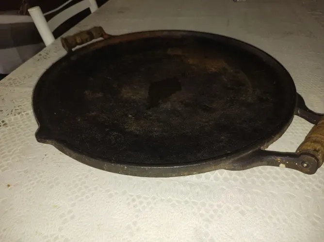 frigideira de ferro fundido rústica ou chapa de ferro com alças de madeira. 