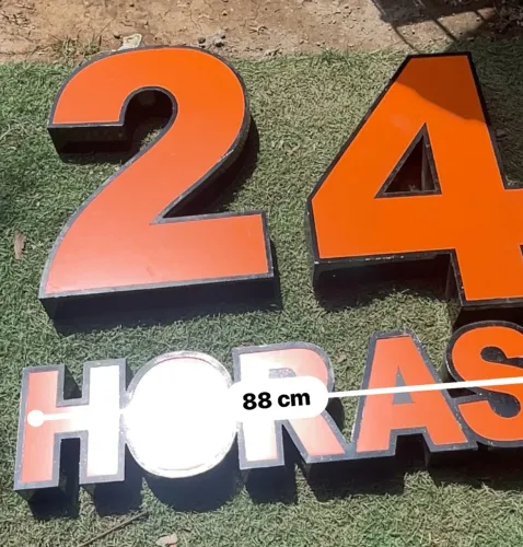 Letreiro face laranja e bordas pretas formando a inscrição "24 HORAS"