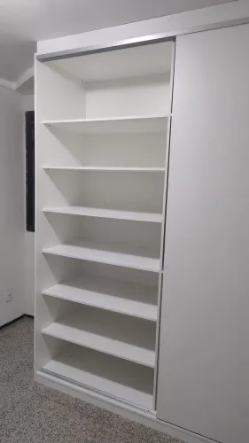 Armário de portas de correr branco com prateleiras e gavetas.