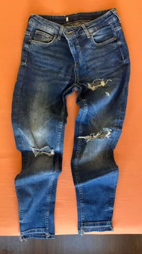 Calça jeans clássica, cor tradicional, com rasgos na frente