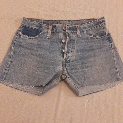 Short de jeans, cortado de calça, acabamento com franjas, em bom estado de conservação.