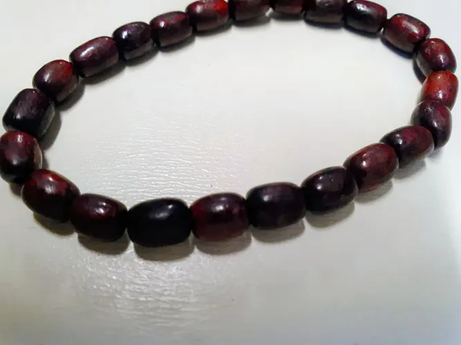 Pulseira feita com contas de madeira em tom avermelhado escuro