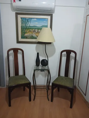 Duas cadeiras de madeira e uma mesinha c abaju