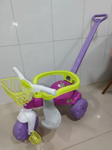 triciclo infantil Magic Toys Tico-Tico Festa Rosa com haste para empurrar.