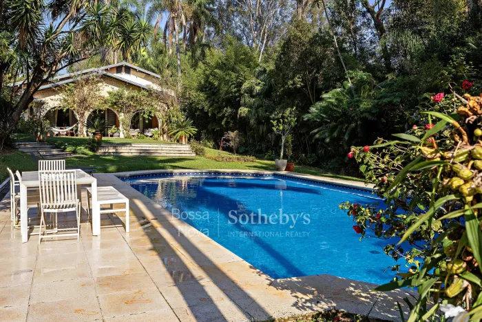 Casa com piscina e quadra de tênis em condomínio rodeado por áreas verdes