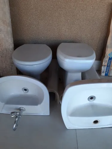 dois vazos sanitários e duas pias de banheiro, uma delas já tem a torneira