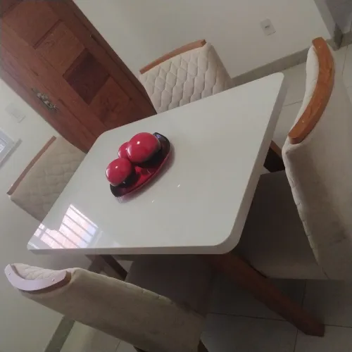 Mesa de jantar moderna e tampo de vidro e cadeiras estofadas e elegantes.