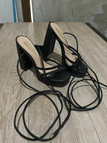 Sandália de salto alto preto com tiras de amarração da marca Gabriela.
