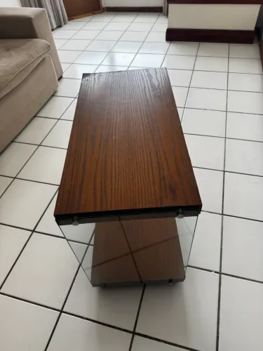 Mesinha de apoio lateral em madeira escura com laterais em vidro temperado.