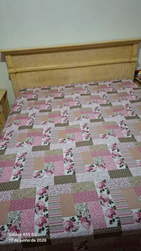 Cama queen sem colchão e duas mesas de cabeceira.