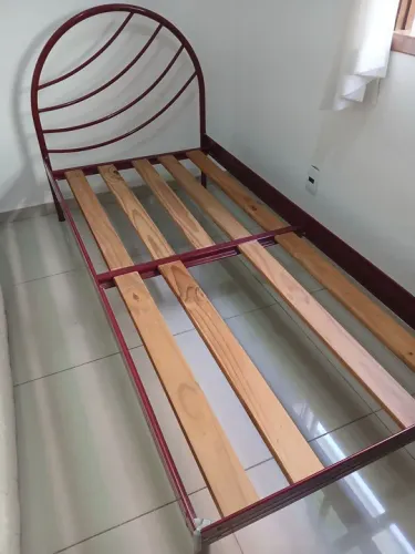 Cama de ferro com estrutura de madeira
