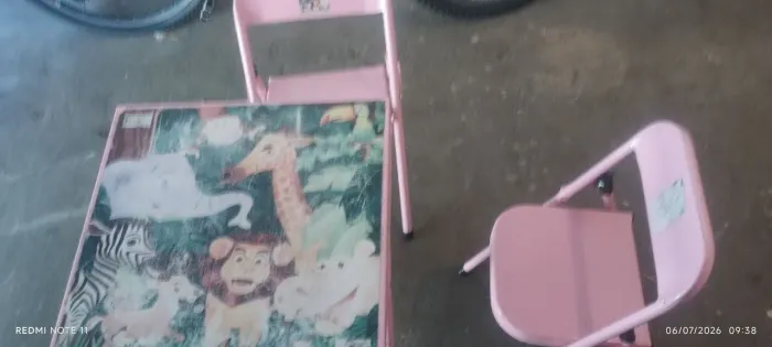 Mesa rosa com duas cadeiras de ferro para criança.